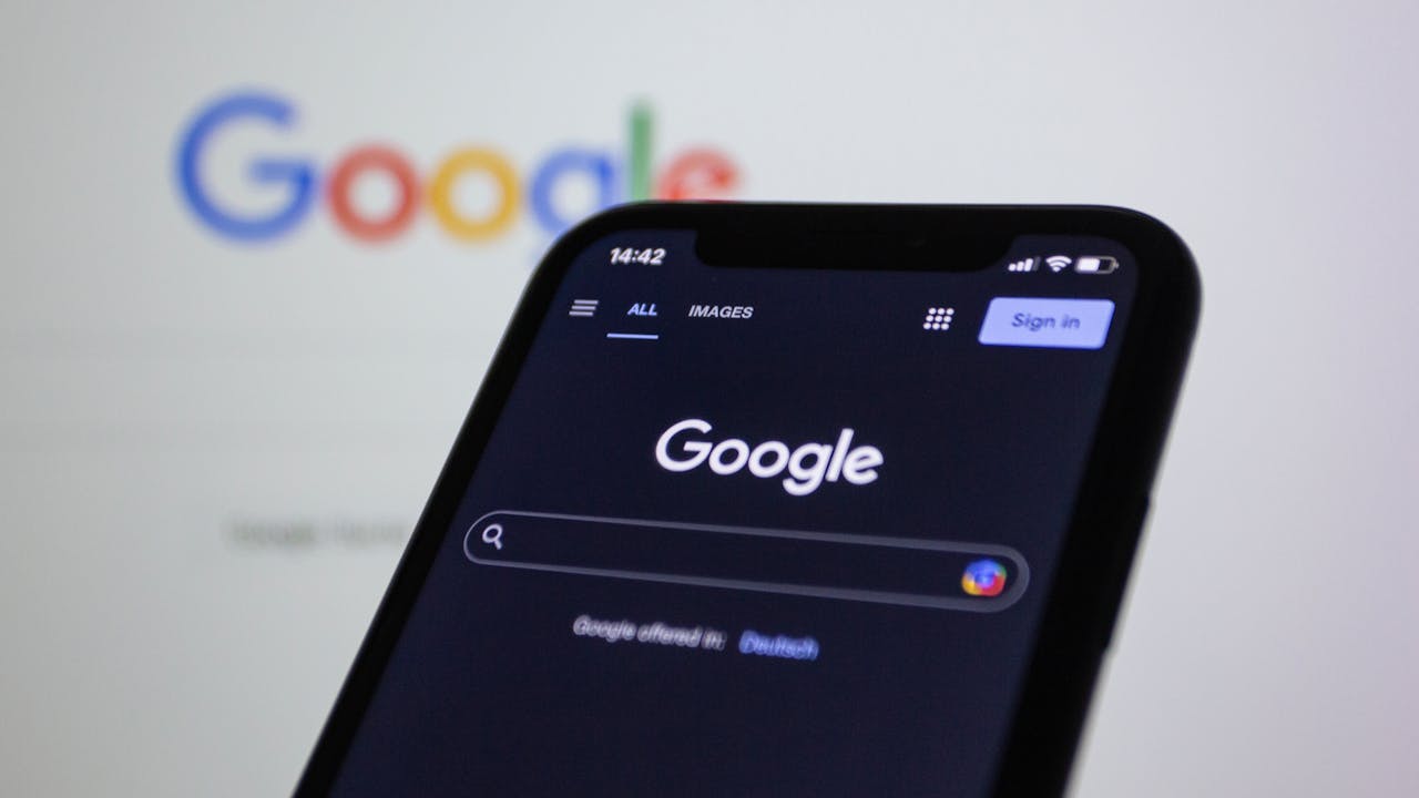 gallery-1 Smartphone screen showing Google search in dark mode with the Google logo in the background.