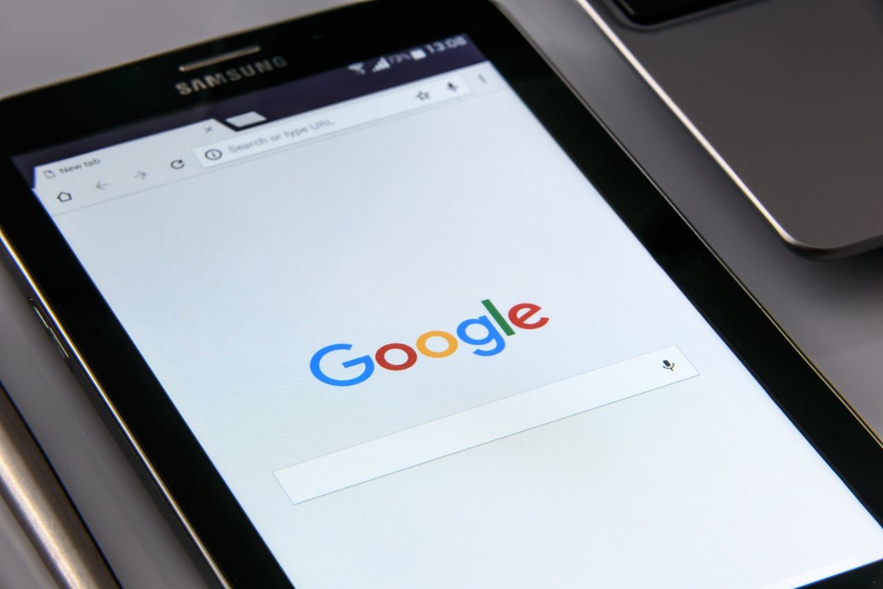 hero-img-01 Close-up of a tablet displaying Google's search screen, emphasizing technology and internet browsing.