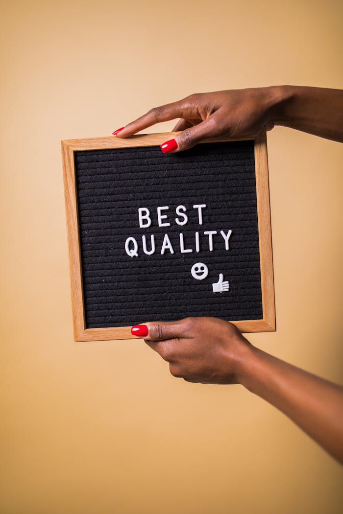 services-02 Hands holding a letter board with 'Best Quality' text, emoji, and thumbs up.