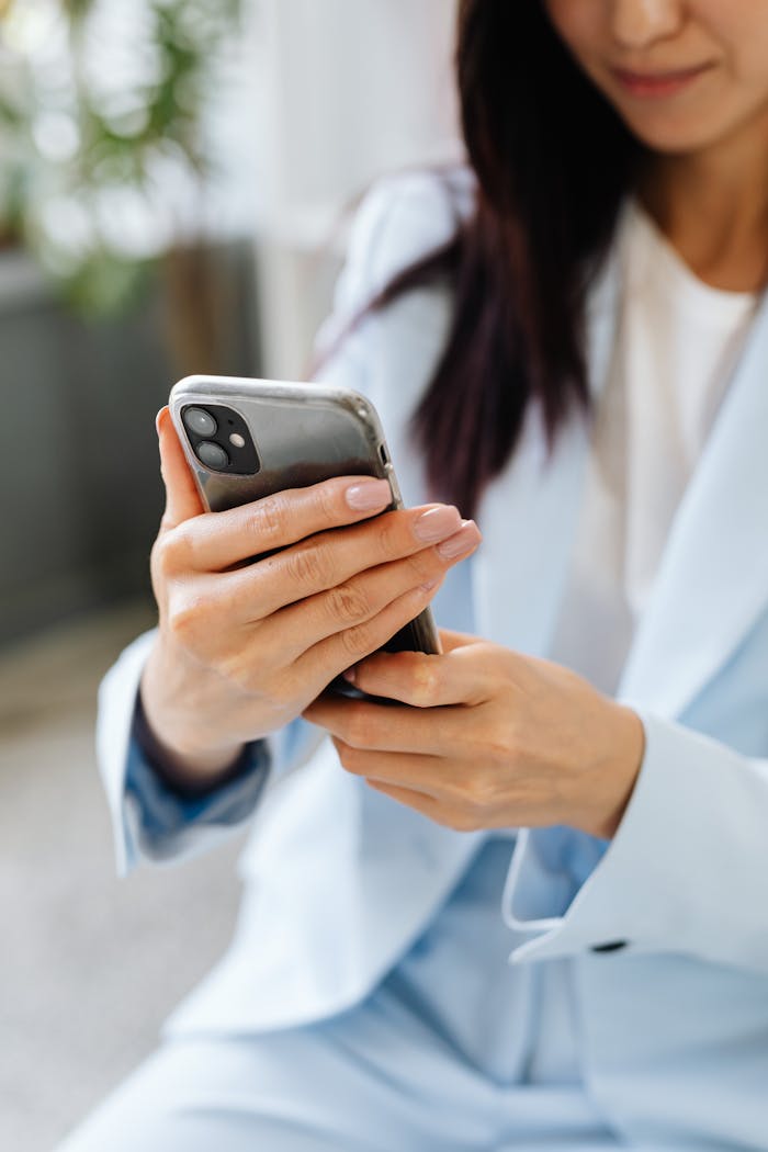 services-img Professional woman in a suit focuses on her smartphone, capturing a casual work moment.
